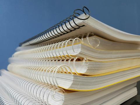 a stack of books bound with black or white plastic spirals